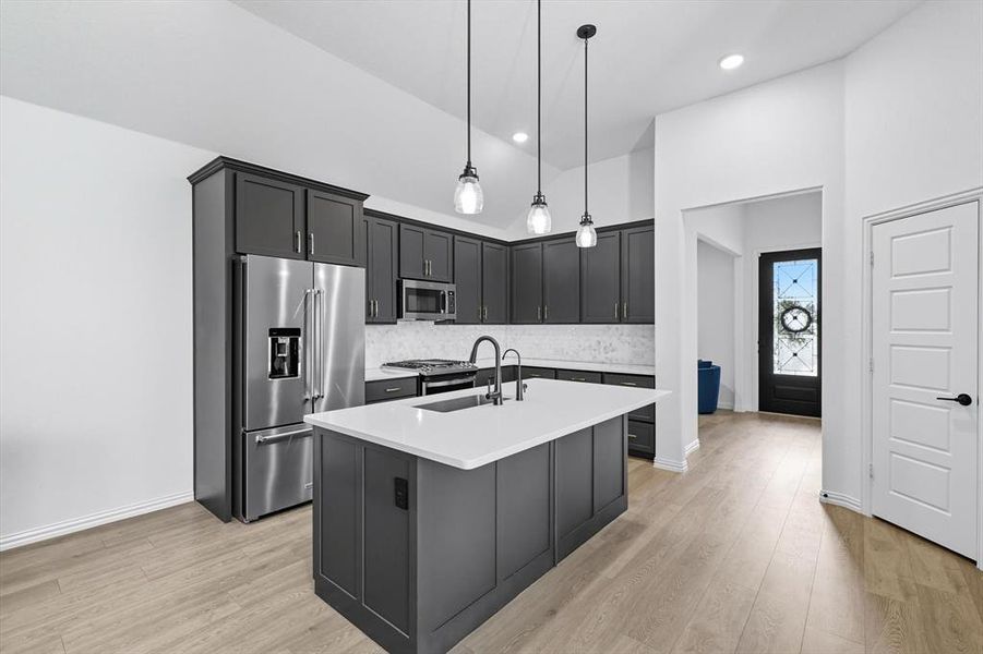 Kitchen featuring stainless steel appliances, pendant lighting, light wood finished floors, backsplash, and recessed lighting