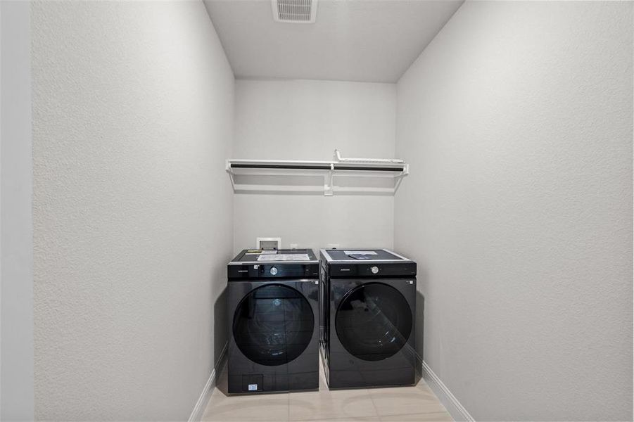 Laundry room with light tile patterned floors and separate washer and dryer