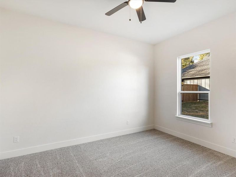Carpeted spare room featuring baseboards and ceiling fan