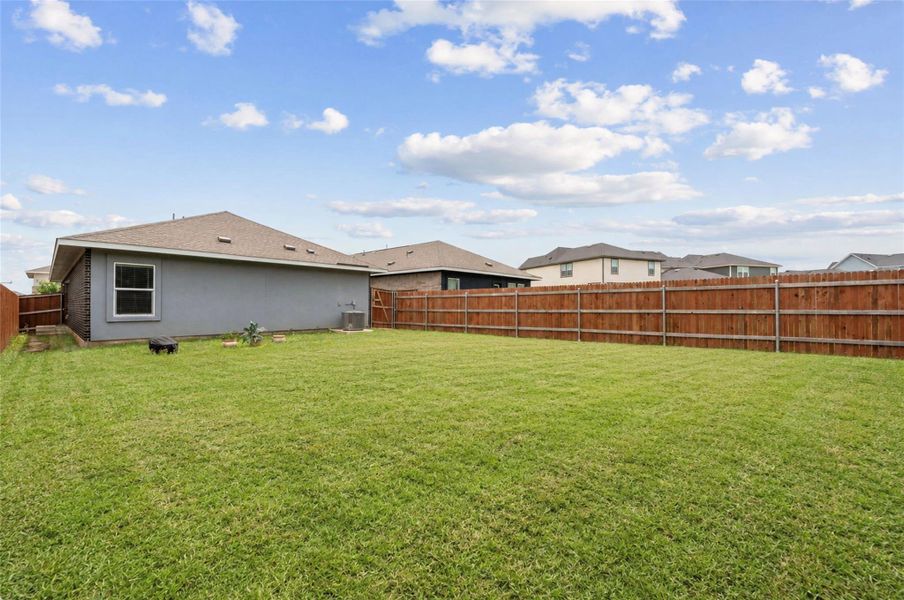 Expansive grassy backyard featuring a full privacy fence