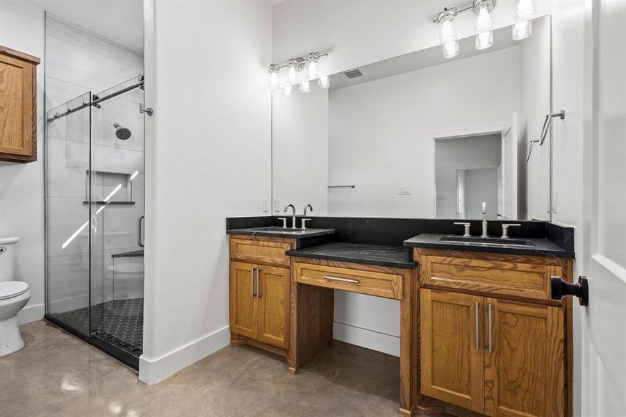 Full bath with finished concrete floors, a stall shower, and double vanity