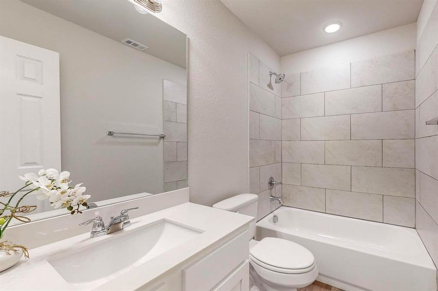 Full bathroom featuring tiled shower / bath combo, vanity, and toilet