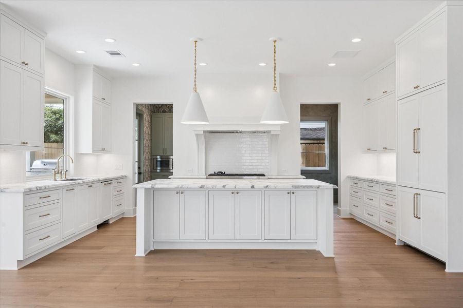 Chef’s kitchen anchored by an oversized quartz island, custom vent hood, and ceiling height cabinetry, featuring designer brass hardware, premium appliance package, and generous counter space designed for both everyday living and elevated entertaining in this Harvard Homes build.