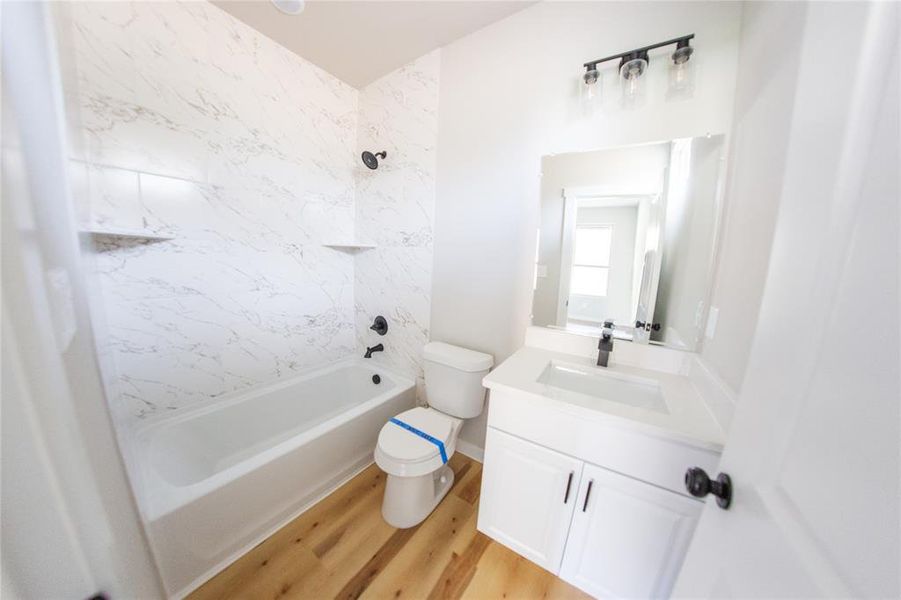 Full bathroom with shower / bathtub combination, vanity, and light wood finished floors