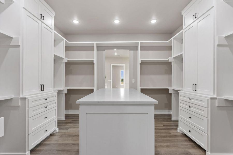 A spacious dressing area with abundant built-in storage and a central island. A spacious dressing area with abundant built-in storage and a central island.
