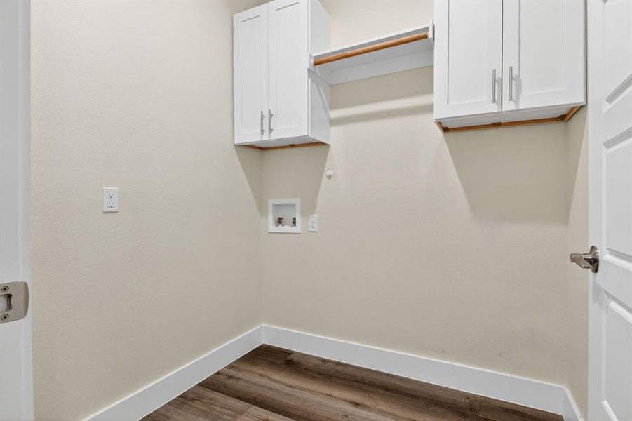 Seperate utility room for washing machine and clothes dryer with white cabinets above and dry rack.