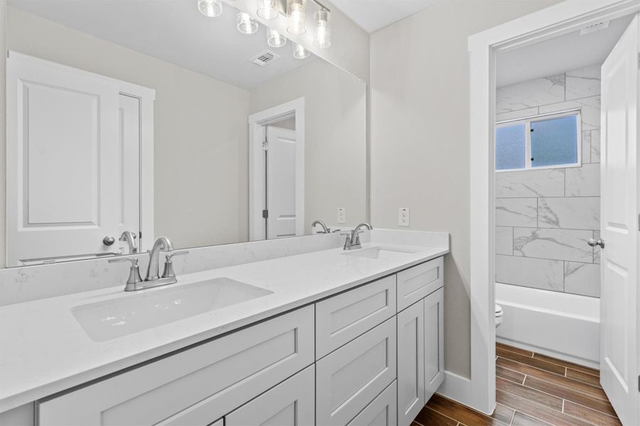 Full bathroom with toilet, vanity, and tiled shower / bath combo