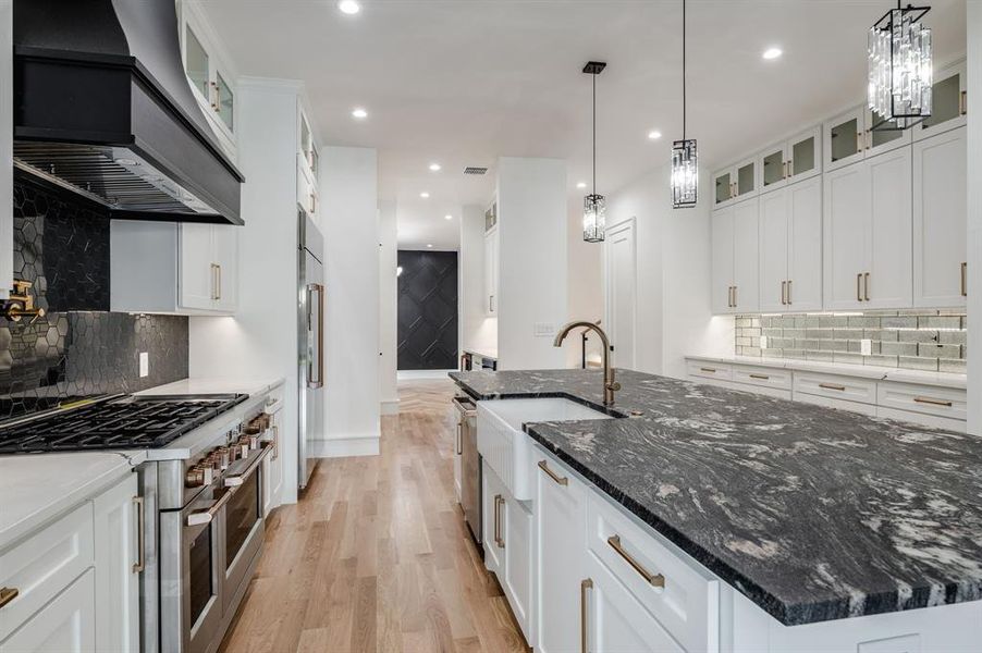 Kitchen with decorative backsplash, glass insert cabinets, dark stone countertops, white cabinets, and recessed lighting Kitchen with decorative backsplash, glass insert cabinets, dark stone countertops, white cabinets, and recessed lighting