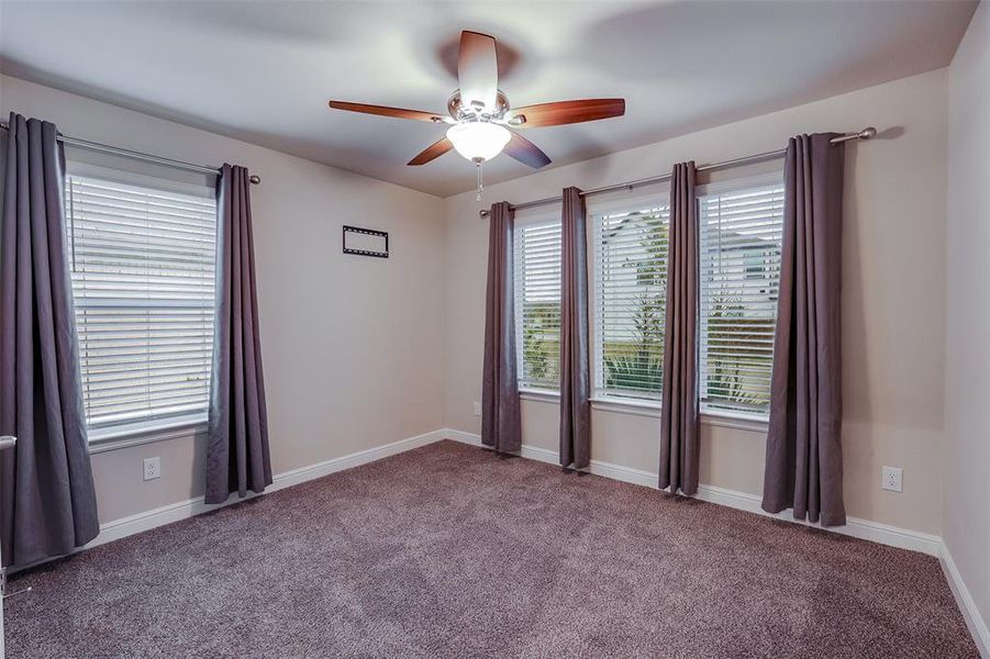 Carpeted spare room featuring a ceiling fan and baseboards Carpeted spare room featuring a ceiling fan and baseboards