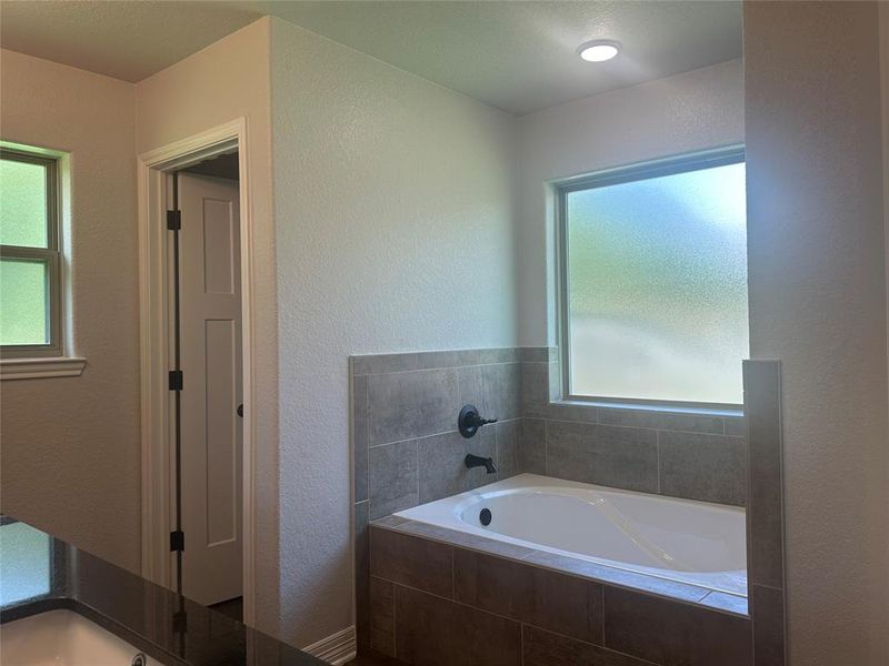 Full bath featuring a bath and a textured wall