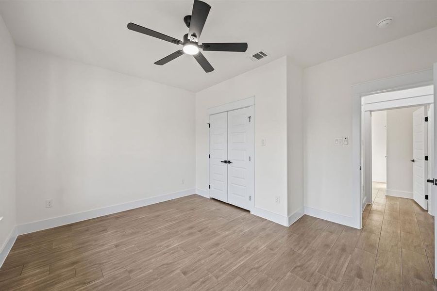 Unfurnished bedroom with light wood-style flooring, ceiling fan, and a closet
