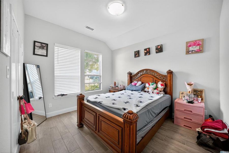 Bedroom featuring wood finished floors and vaulted ceiling