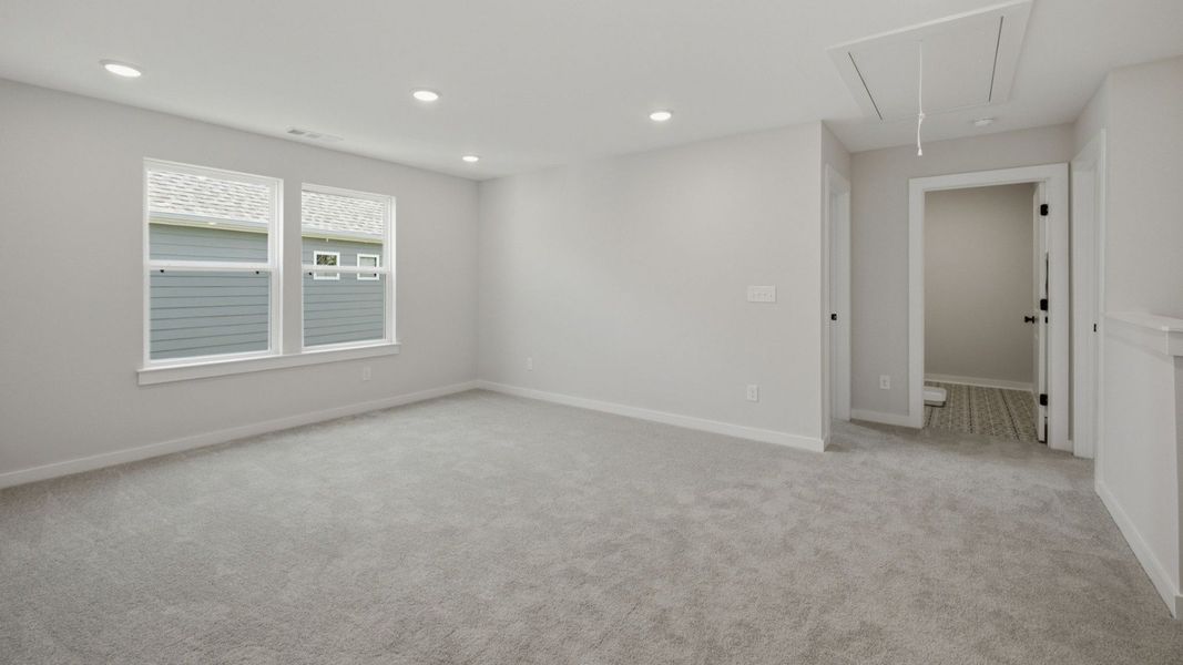 Loft with access to bedrooms with carpet and windows
