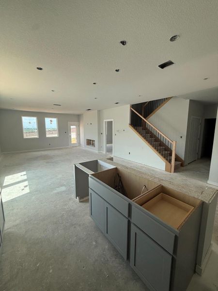 Unfinished interior space offers an open-concept living area with an island and a striking staircase. Unfinished interior space offers an open-concept living area with an island and a striking staircase.