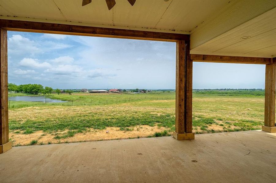 View of yard with a water view, a patio, a ceiling fan, and a rural view