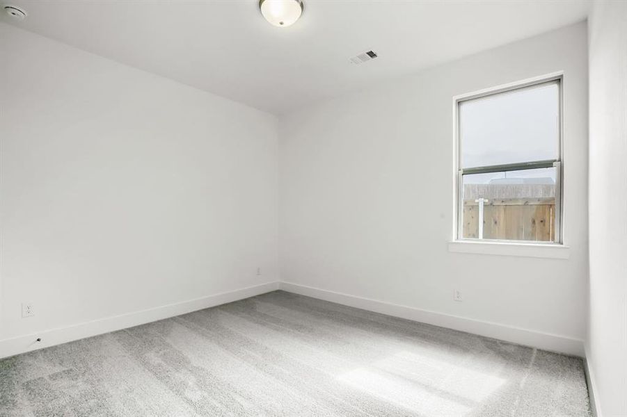 Bright room featuring neutral gray carpeting, white painted walls, a single window, and a flush mount ceiling light fixture