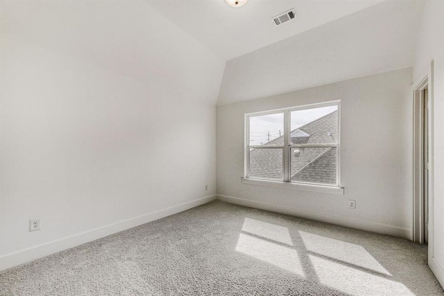 Empty room featuring light colored carpet and vaulted ceiling