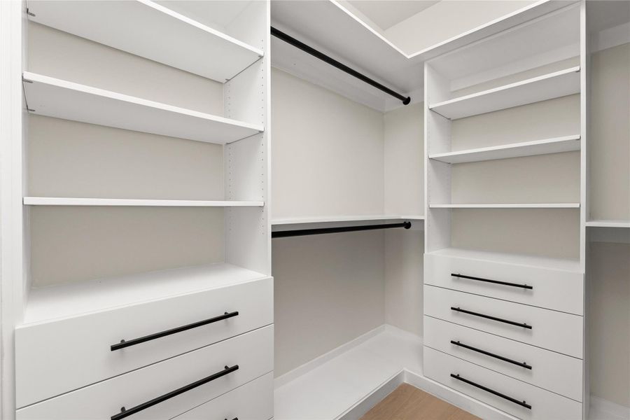 Custom floor-to-ceiling shelving and integrated drawers maximize storage in this walk-in closet.