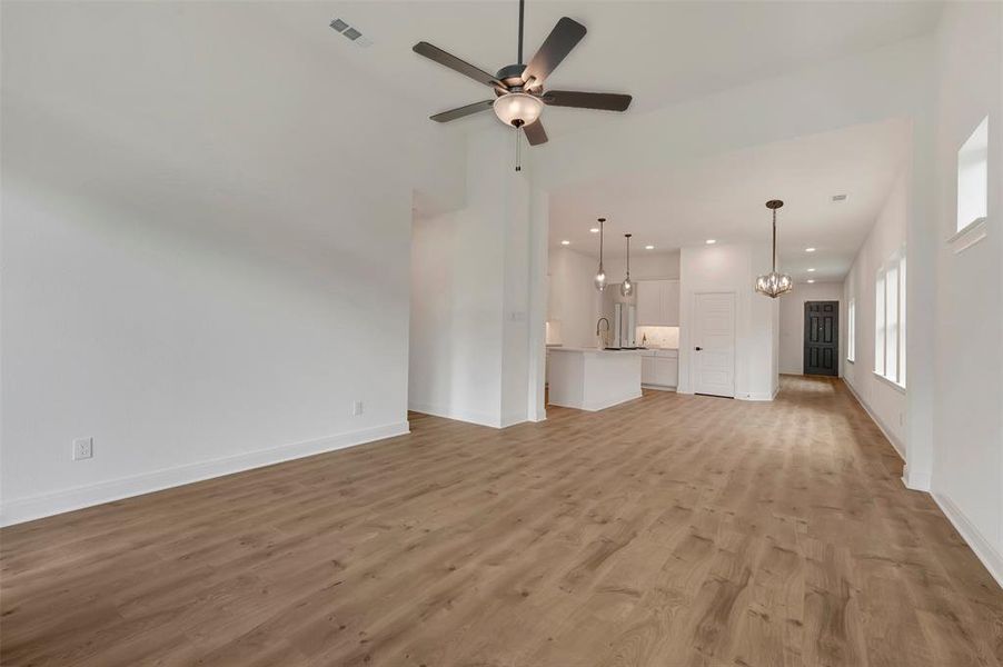 Open-concept living space featuring wood-finish flooring, a vaulted ceiling, and a ceiling fan with integrated lighting