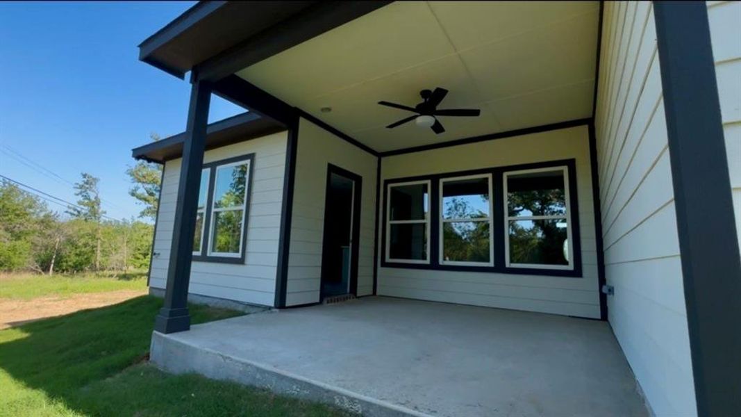 Covered outdoor patio  black ceiling fan, and multiple exterior windows