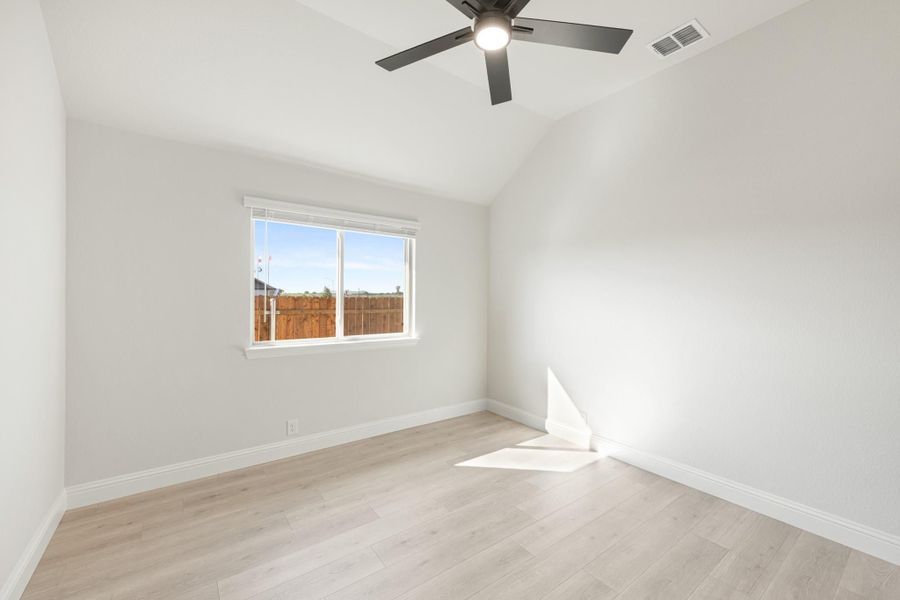 Empty bedroom with vaulted ceiling, ceiling fan, light wood floors, and single window