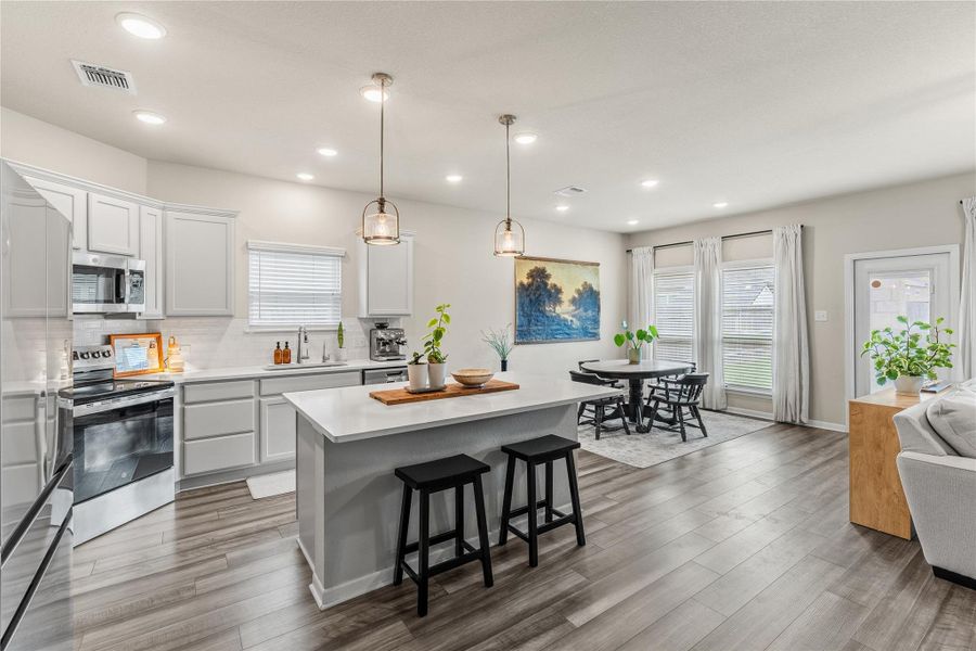 A naturally illuminated open-concept kitchen and dining area features sleek appliances and ample counter space. A naturally illuminated open-concept kitchen and dining area features sleek appliances and ample counter space.