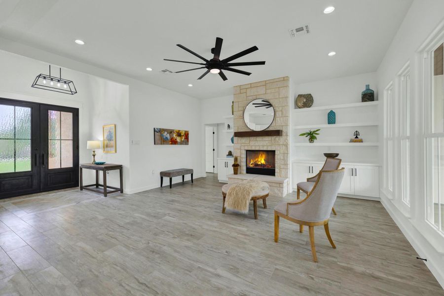 Living area featuring wood-finish flooring and a stone-clad fireplace with a wooden mantel