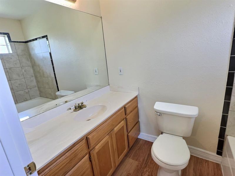 Bathroom with shower / tub combination, vanity, and dark wood-style flooring