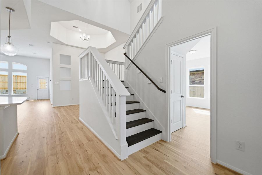 Stairs with wood finished floors, healthy amount of natural light, and a high ceiling