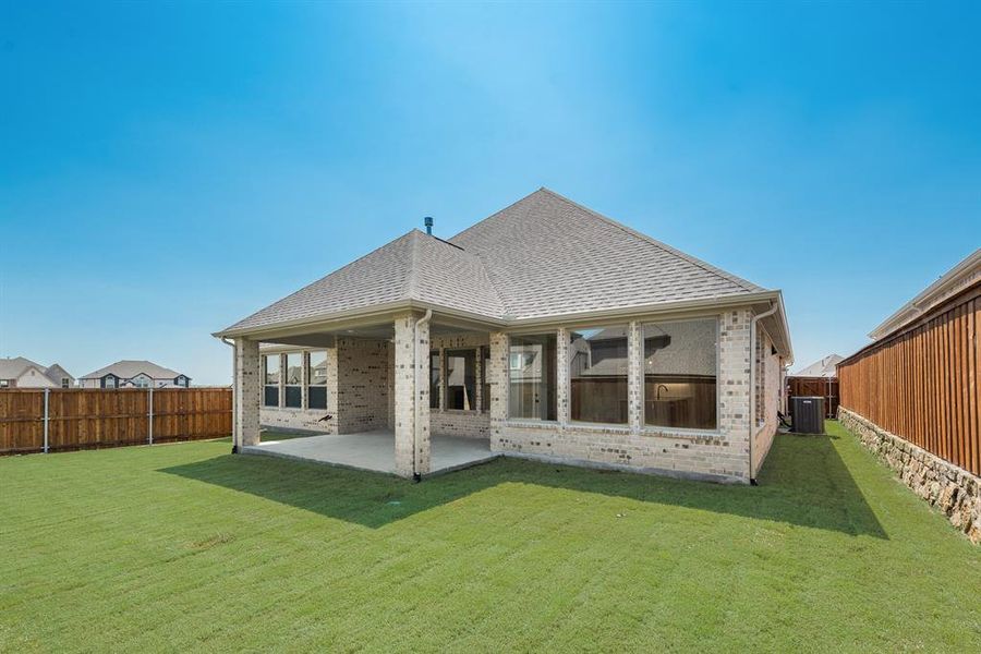 Back of property with brick siding, a patio, a fenced backyard, and roof with shingles