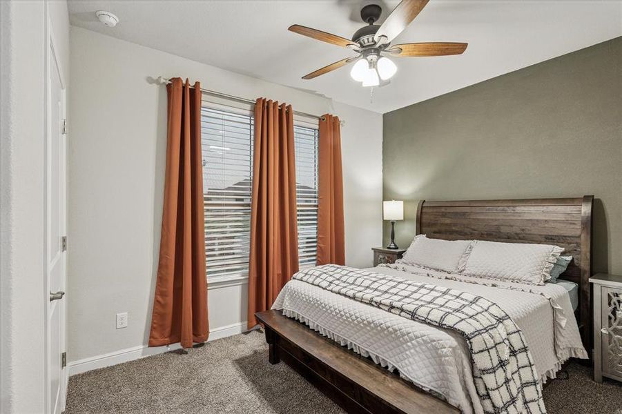 Bedroom No. 4 with ceiling fan, accent wall, and light carpeting Bedroom No. 4 with ceiling fan, accent wall, and light carpeting