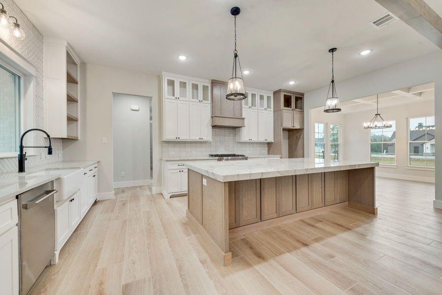 Kitchen featuring white cabinetry, stainless steel dishwasher, a large island, and light wood-type flooring