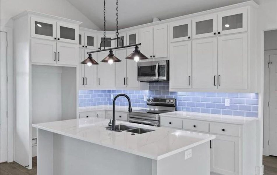 Kitchen with pendant lighting, a center island with sink, white cabinets, light stone countertops, and stainless steel appliances