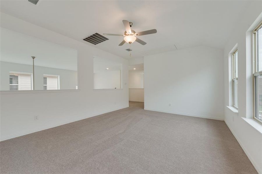 Spare room with light colored carpet, ceiling fan, and a healthy amount of sunlight