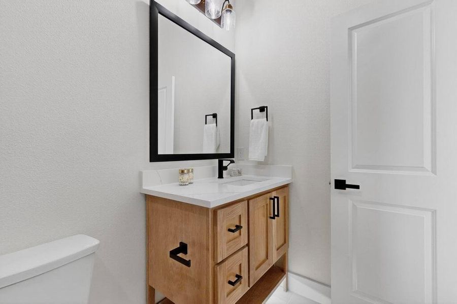 Half bath featuring vanity and toilet Half bath featuring vanity and toilet
