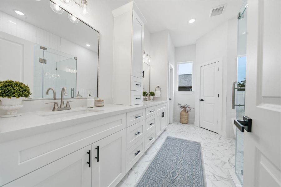 The primary bathroom gives spa vibes with high-end tile and large vanity with ample storage.