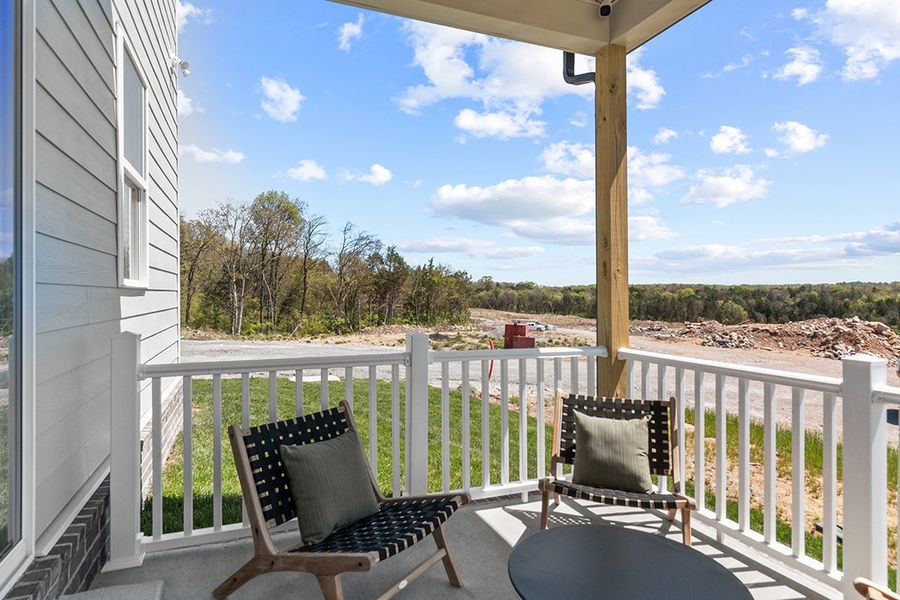 A deck with chairs and a table on it by a building.