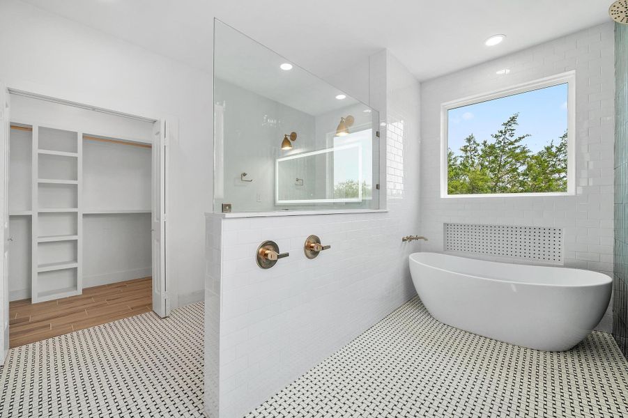 Bathroom with a walk in shower, a soaking tub, a spacious closet, tile walls, and recessed lighting Bathroom with a walk in shower, a soaking tub, a spacious closet, tile walls, and recessed lighting
