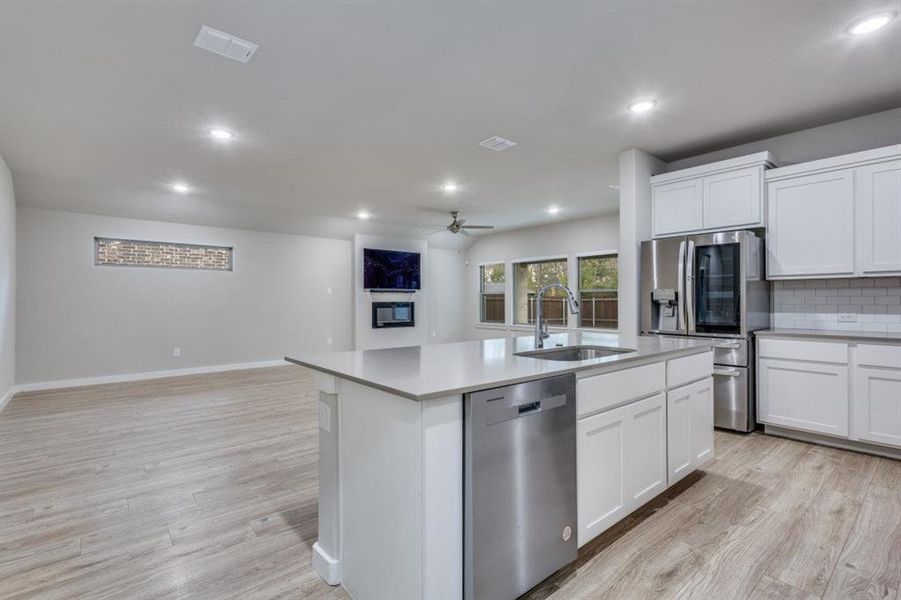 Kitchen with open floor plan, stainless steel appliances, white cabinetry, light wood-type flooring, and recessed lighting Kitchen with open floor plan, stainless steel appliances, white cabinetry, light wood-type flooring, and recessed lighting