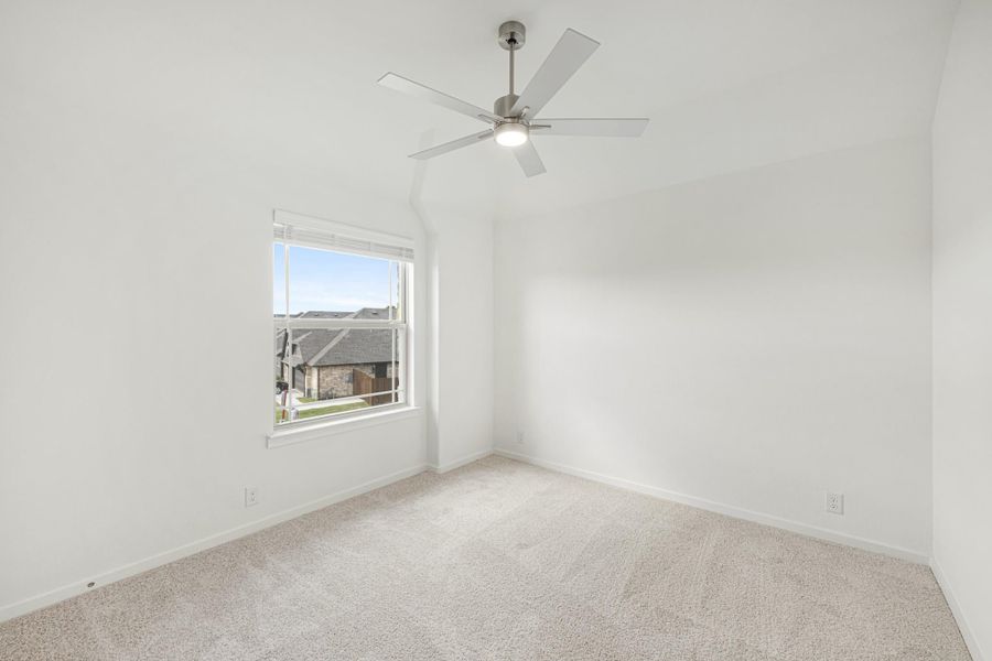 Empty bedroom with vaulted ceiling, ceiling fan, carpet flooring, and a single window with neighborhood view