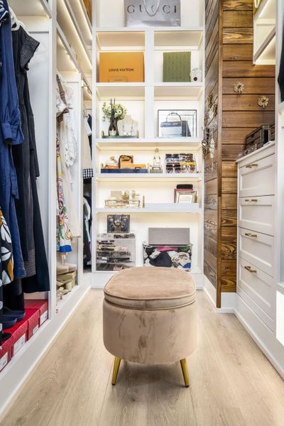 Custom shelving and recessed lighting illuminate this well-organized closet with ample storage solutions.