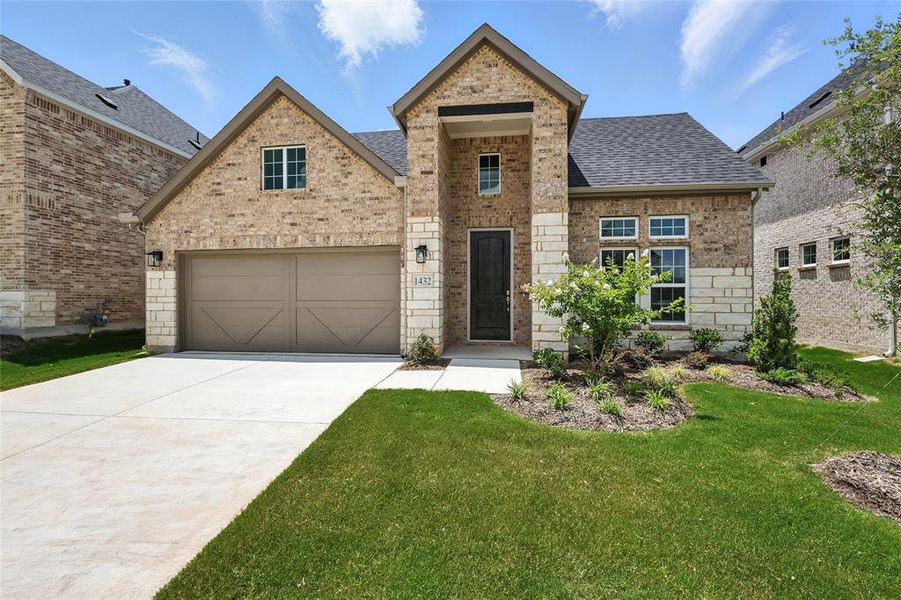 View of front of home featuring brick siding, roof with shingles, driveway, a front lawn, and a garage