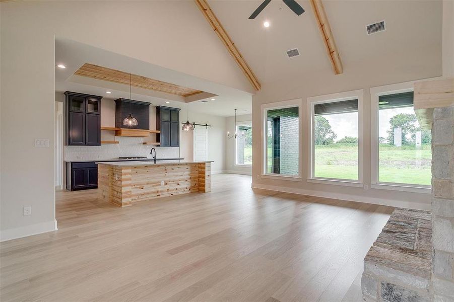 Unfurnished living room with light hardwood / wood-style floors, sink, high vaulted ceiling, and ceiling fan