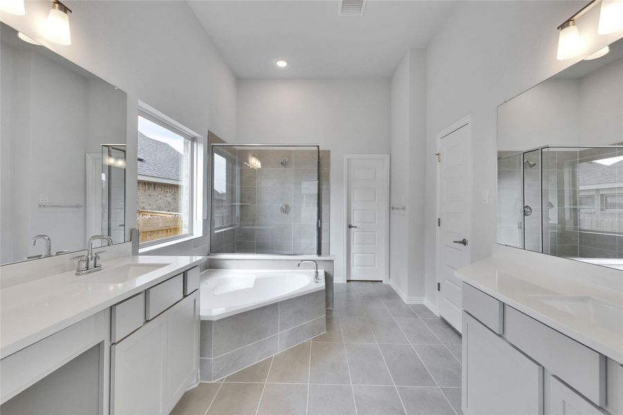 Bathroom with two vanities, a shower stall, light tile patterned flooring, a bath, and recessed lighting Bathroom with two vanities, a shower stall, light tile patterned flooring, a bath, and recessed lighting