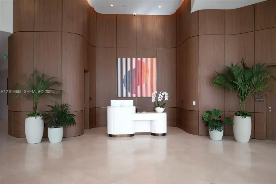 Curved wood-paneled feature walls, large-format tile flooring, and custom built-in reception desk with a tiered profile
