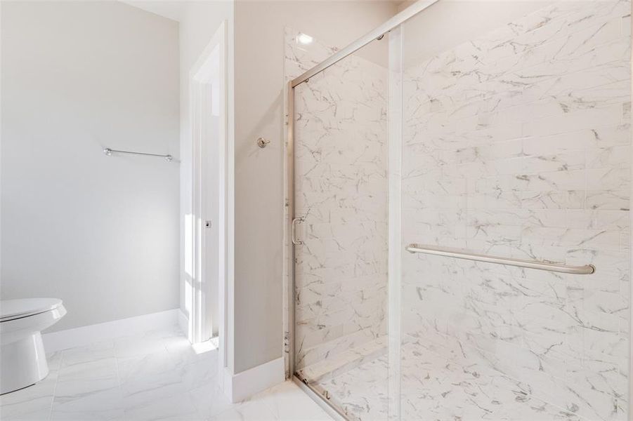 Bathroom featuring toilet, walk in shower, and tile patterned flooring