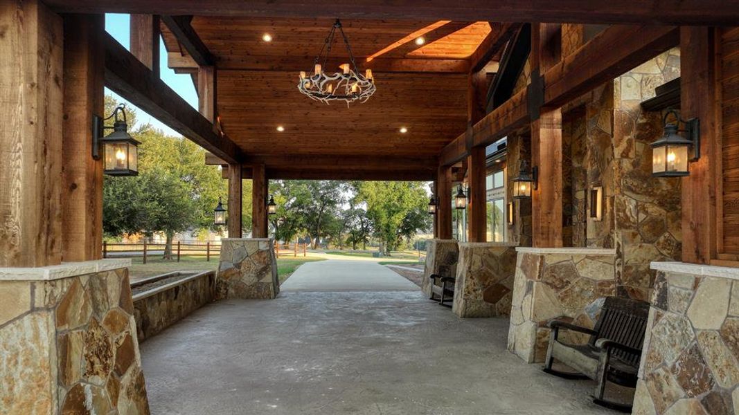 Covered entry with rustic stonework, wood beams, and chandelier detail creates a warm and inviting first impression.