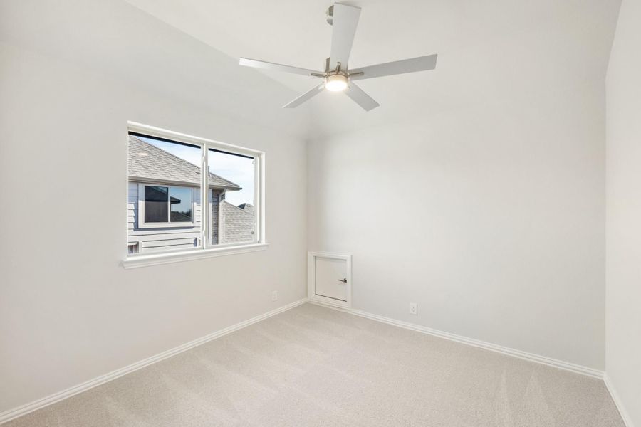 Empty bedroom with carpet, ceiling fan, vaulted ceiling, and single window overlooking neighboring home Empty bedroom with carpet, ceiling fan, vaulted ceiling, and single window overlooking neighboring home