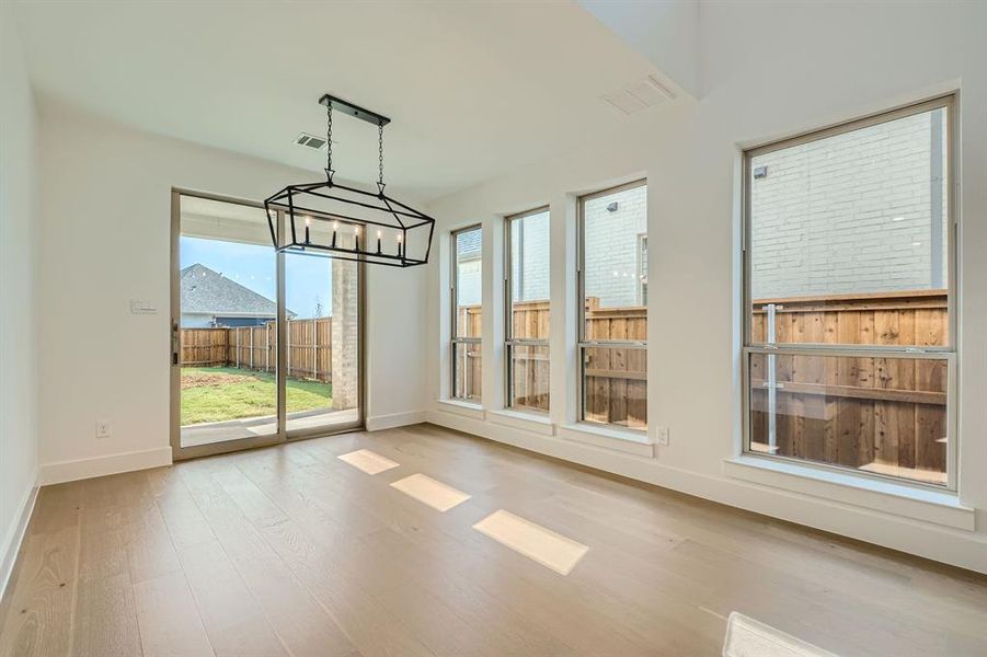 Unfurnished dining area with an inviting chandelier and light hardwood / wood-style flooring