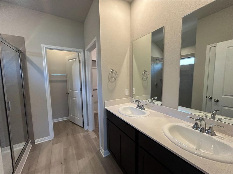Full bathroom with wood finished floors, a shower stall, and double vanity Full bathroom with wood finished floors, a shower stall, and double vanity